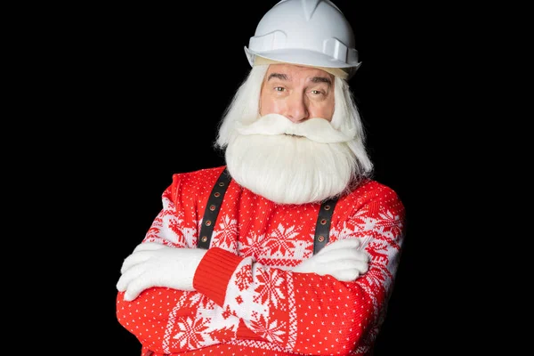 Gri sakallı ve kasklı, elleri katlı, Noel Baba süveteri giyen yaşlı bir adam siyah bir arka plana karşı duruyor. Profesyonel Noel arifesi konsepti.