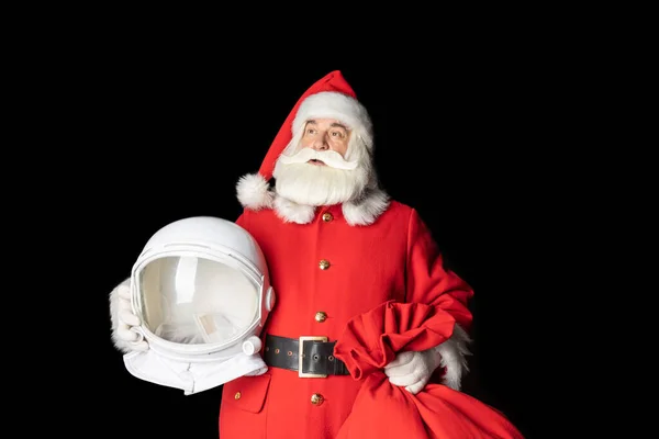 Noel Baba bir astronotun miğferini elinde tutuyor ve boşluğa bakıyor. Uzağa. Siyah arkaplanda yakın plan.