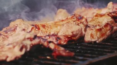 Yakın planda ızgara et parçaları. Ateşteki et. Kavrulmuş et bifteği, baharat ve otlarla birlikte BBC ızgarasında yanan kömürler, alevler ve ağır çekimde duman. Barbekü ızgarası