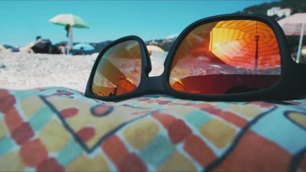 De glazen staan op het strand. De reflectie in de bril. Tijd verstrijkt. Rust en ontspanning concept Stockvideo's