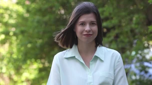 Porträt eines jungen brünetten Mädchens im Alter von 30-35 Jahren, blickt in die Kamera und lächelt — Stockvideo