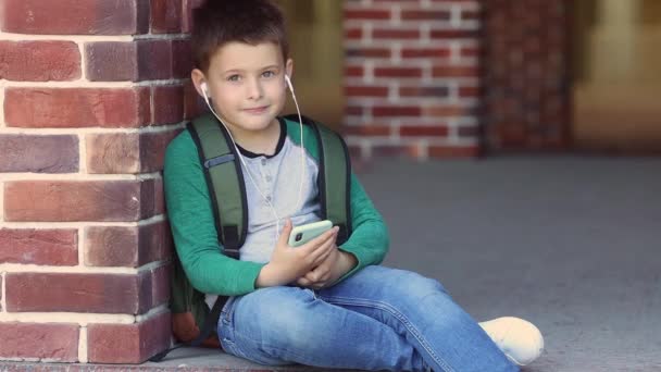 Ragazzo Della Scuola Ascolta Musica Con Cuffie Siede Con Telefono — Video Stock