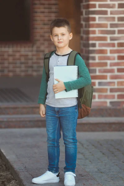 Glimlachend jongetje 6-7 jaar oud gaat naar school in casual kleding en rugzak — Stockfoto