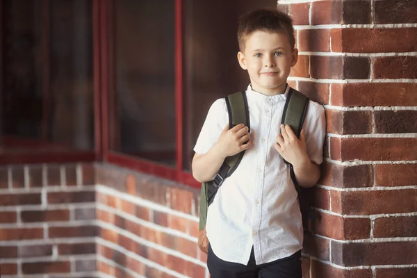 Glimlachend jongetje 6-7 jaar oud gaat naar school in uniform en rugzak — Stockfoto