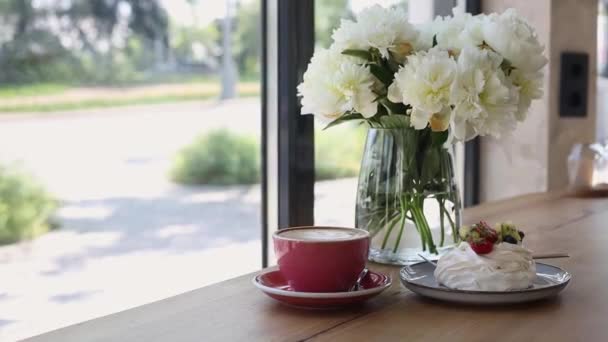 Xícara de café rosa cappuccino e sobremesa cremosa com frutas na mesa perto da janela — Vídeo de Stock
