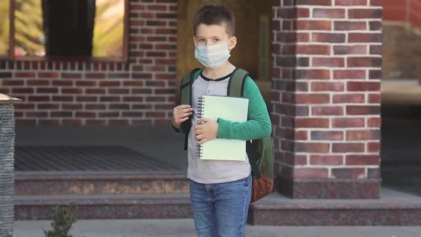 Μικρό αγόρι με προστατευτική ιατρική μάσκα στο πρόσωπό του πίσω στο σχολείο. Νέο φυσιολογικό. — Αρχείο Βίντεο