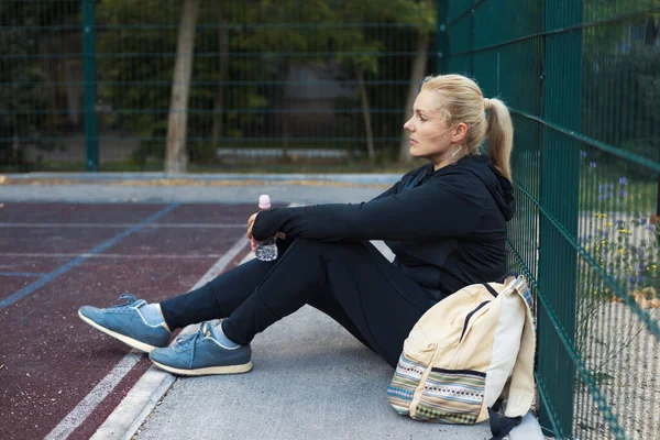 Spor yaptıktan sonra sokakta spor yapan şişman, aktif genç bir kadın. Spor giyim bölümündeki yorgun sarışın kız dışarıda antrenman yaparak kilo vermeye çalışıyor. Yaşam tarzı sağlıklı konsept.