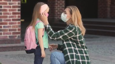 Anne küçük kızını okula götürür, sarılır ve yeni normal Coffid-19 'la ilgilenir..