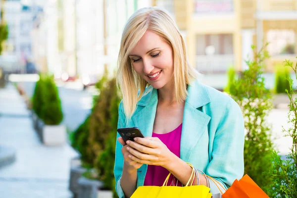 Покупательница с сумками разговаривает по телефону на открытом воздухе — стоковое фото