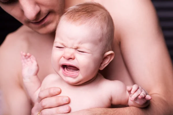 Joven padre está alimentando a su hija bebé.niña llorando a manos del padre —  Fotos de Stock