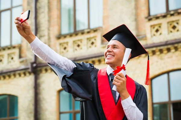 Graduating boy take a picture on cell phone — Stock Photo, Image