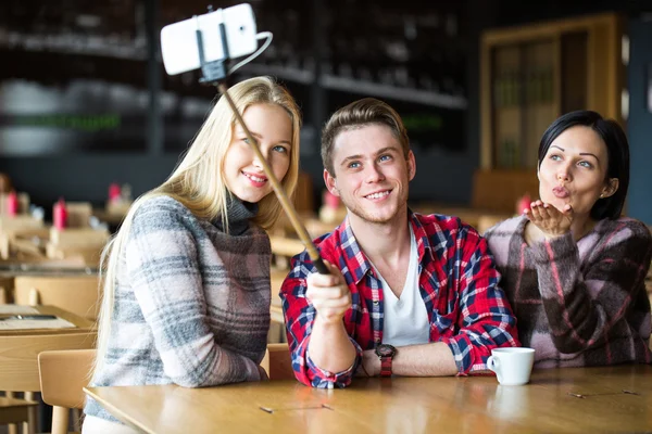 students make selfie in a cafe. Boy and two girls make selfie in cafe