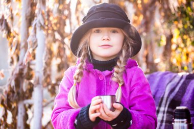sonbahar parkta kahve veya çay içme şapkalı güzel küçük sarışın kız. Çocuk parkta çay içmek