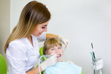Young handsome dentist treats tooth child, a woman dentist