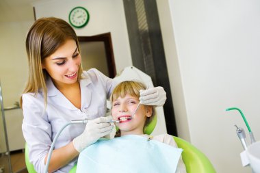 Young handsome dentist treats tooth child, a woman dentist