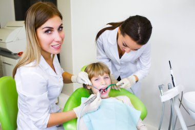 Young handsome dentist treats tooth child, a woman dentist