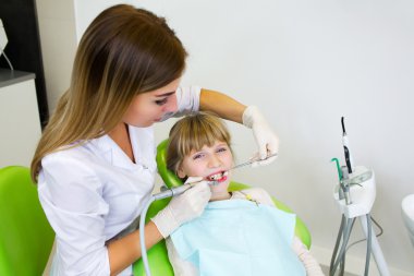 Young handsome dentist treats tooth child, a woman dentist