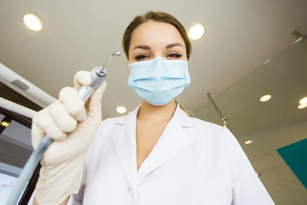 Young women dentist with sterile mask readily approaching a patient with dental instruments held in the hands protected with surgical gloves young dentist with sterile mask — Stock Photo, Image