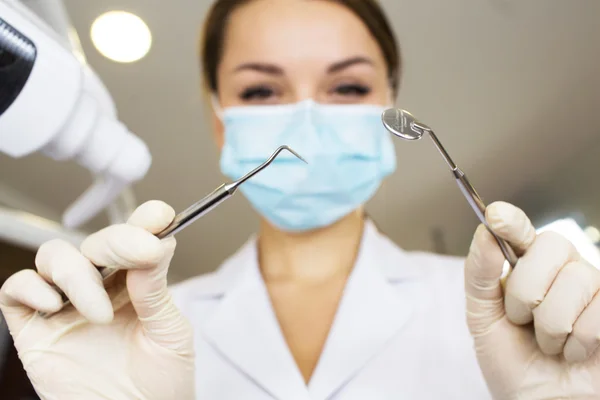 Young women dentist with sterile mask readily approaching a patient with dental instruments held in the hands protected with surgical gloves young dentist with sterile mask — Stock Photo, Image