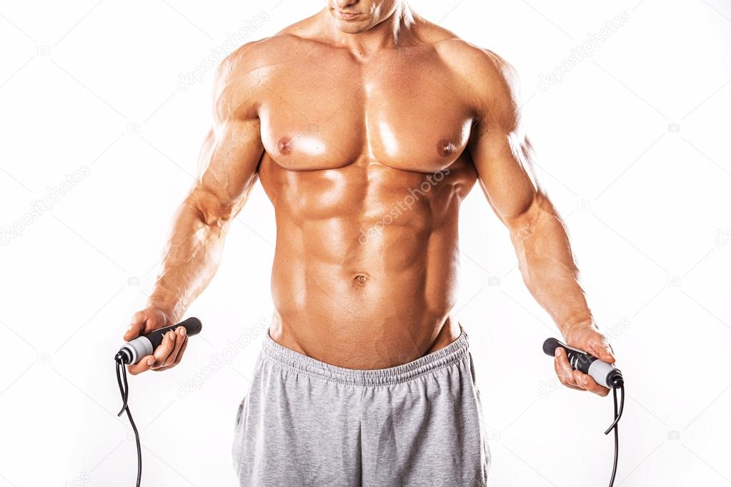 Strong Athletic Man showing muscular body and sixpack abs over white background. Portrait of muscular young man exercising with jumping rope.Muscular man on white background