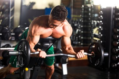 kaslı vücut geliştirmeci biri dumbbells ile yapıyor