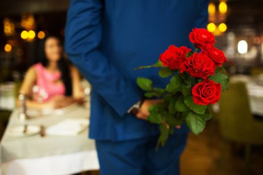 restoranda kırmızı gül arkasına saklanmış adam