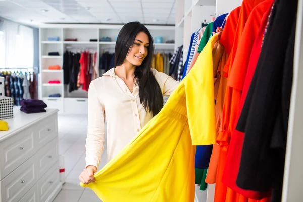 Hermosa joven mide el vestido en la shop.girl en una compra — Foto de Stock