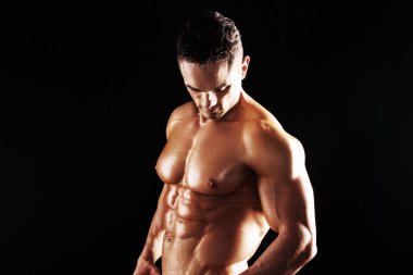 Güçlü atletik kas vücut siyah bir arka plan üzerinde gösterilen adam. Kaslı adam siyah arka plan üzerine