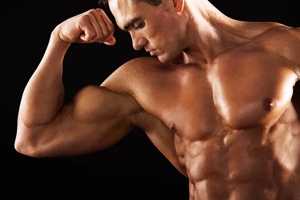 强在黑色背景上显示肌肉发达的身体健壮的男人。在黑色背景上的肌肉男 — 图库照片