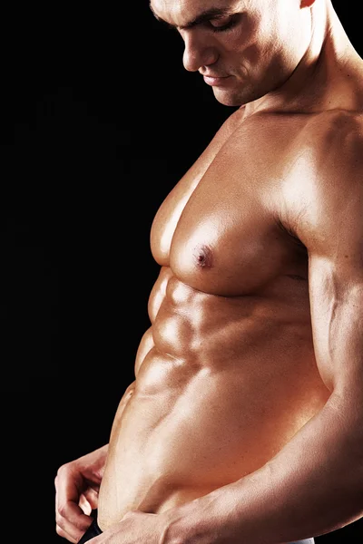 Homem Atlético Forte mostrando corpo muscular em um fundo preto.Homem muscular em fundo preto — Fotografia de Stock