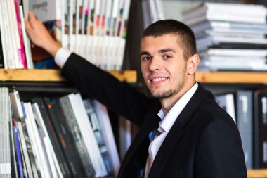 Öğrenci bir kitap seçerek bir kütüphane. genç adam bir kitap kütüphanede seçer.