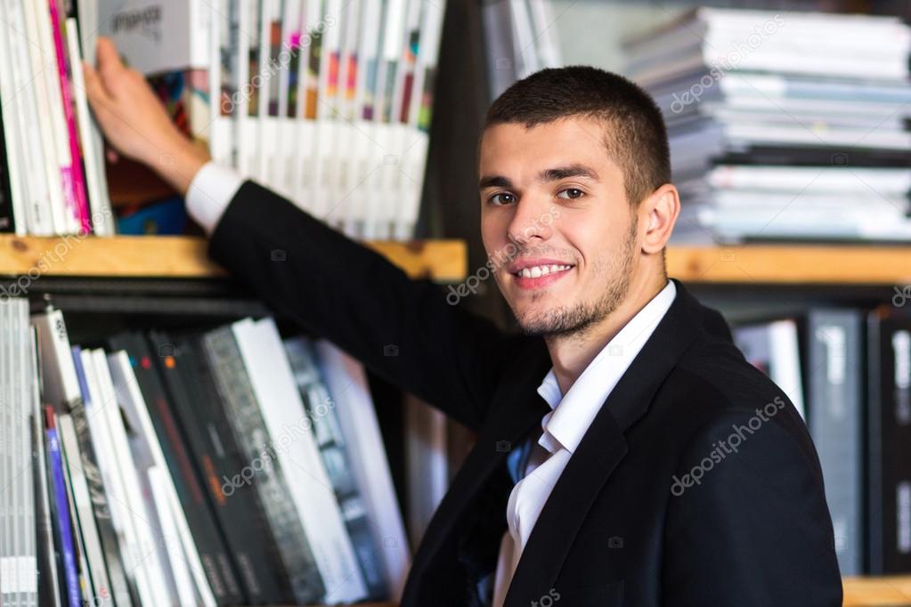 Student in a library choosing a book. young man chooses a book in the library