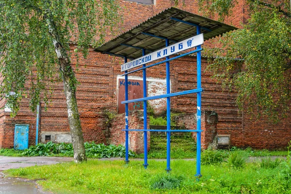 Un club abandonado en un pueblo pequeño. un camino cubierto de hierba y una puerta vieja. tablero de póster en blanco —  Fotos de Stock