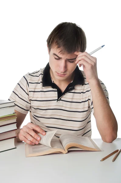 Студент-мужчина за столом с грудой книг — стоковое фото