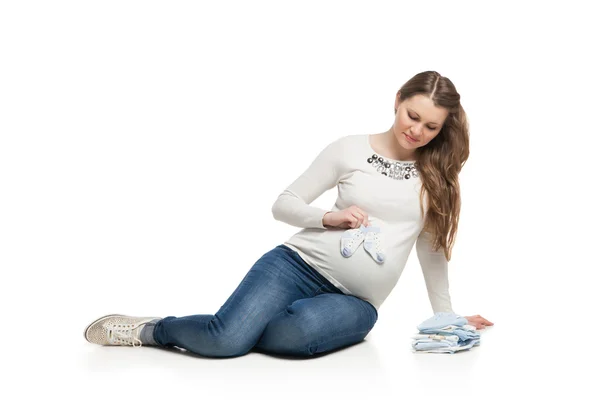 Glückliche schwangere Frau mit Kinderkleidung — Stockfoto