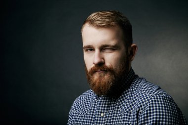 Sakallı adam stüdyo portre koyu arka plan üzerinde kırmızı göz kırpıyor