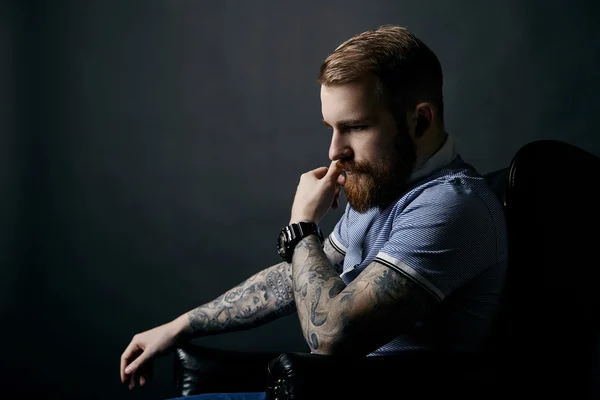 Thoughtful red bearded man studio portrait on dark background