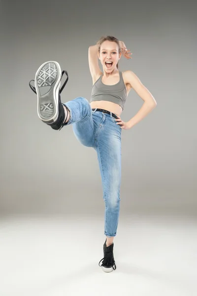 Cheerful young woman kicking with leg in sneakers — Stock Photo, Image
