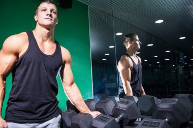 Yakışıklı vücut geliştirmeci ağır dumbbell tutarak yan görünüm