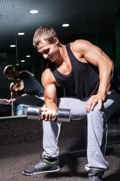 Culturista sonriente haciendo ejercicio en bíceps con mancuerna — Foto de Stock