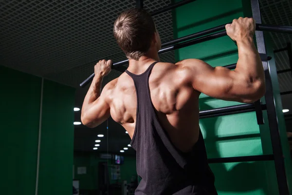 Achteraanzicht van jonge man doen van pull ups — Stockfoto