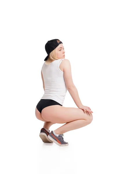 Vrouwelijke model in tank top en slip squating op lendestuk geïsoleerd — Stockfoto