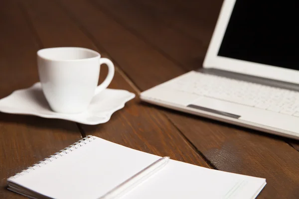 Kopje koffie, notitieboekje en laptop op tafel — Stockfoto