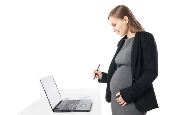 W ciąży kobieta uśmiecha się w dół podczas pracy na laptopie — Zdjęcie stockowe