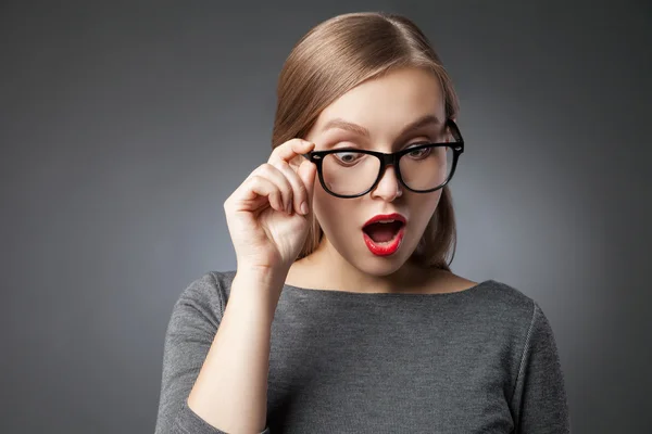 Frau mit großen Augen und Brille blickt erstaunt nach unten — Stockfoto