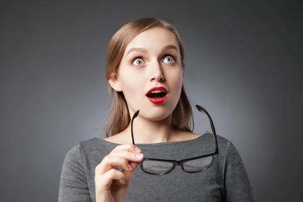 Mujer asombrada sosteniendo gafas mientras mira hacia arriba — Foto de Stock