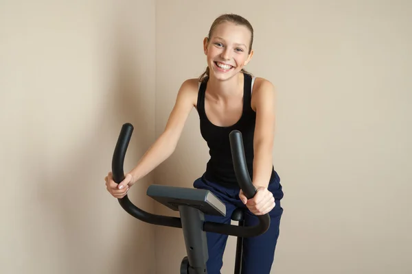 Sonriente adolescente chica ciclismo en casa — Foto de Stock