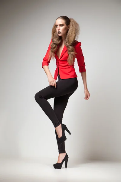 Модель в червоній куртці і чорних високих підборах дивиться геть — стокове фото