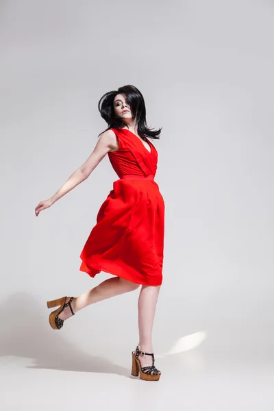 Black-haired woman twisting in red dress — Stock Photo, Image