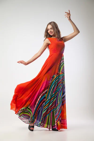 Beautiful young woman in bright colorful dress dancing — Stock Photo, Image